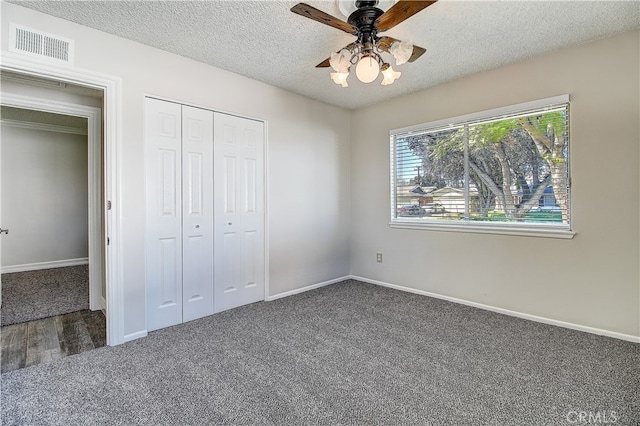 unfurnished bedroom with carpet, a closet, visible vents, a textured ceiling, and baseboards