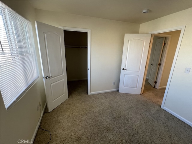 unfurnished bedroom featuring carpet floors, a closet, a spacious closet, and baseboards