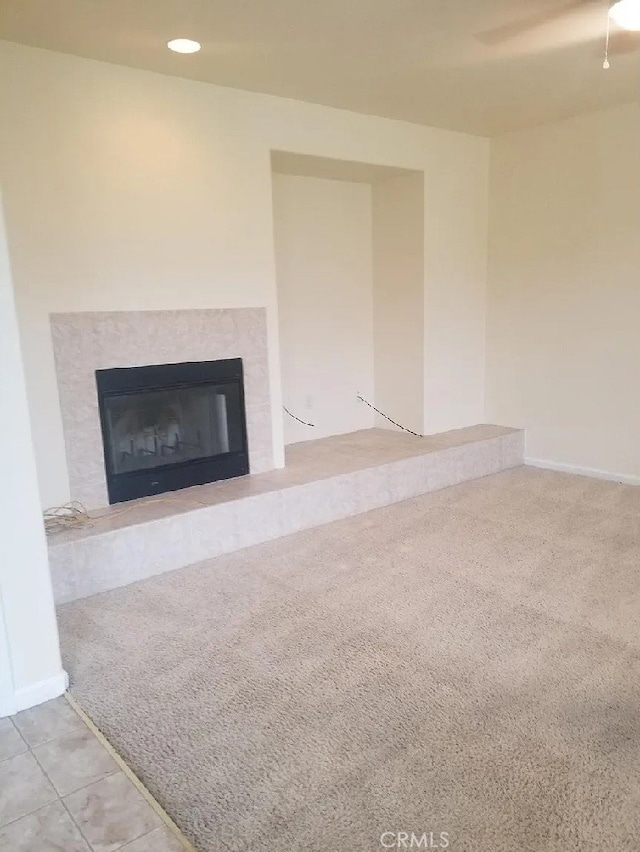 unfurnished living room featuring recessed lighting, carpet flooring, a fireplace with raised hearth, and baseboards