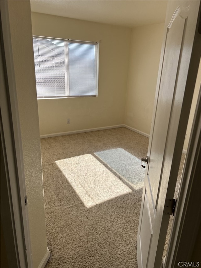 carpeted spare room featuring baseboards