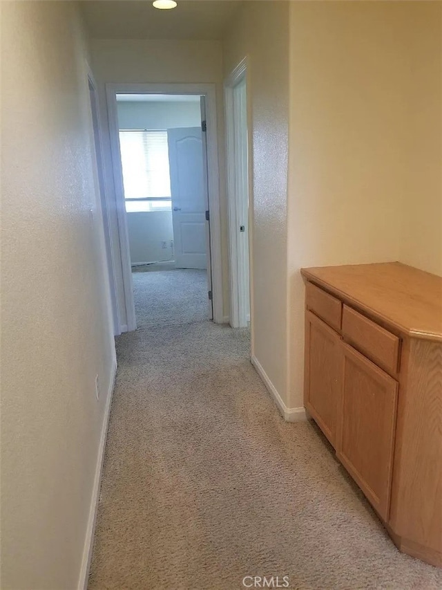 corridor with light colored carpet and baseboards