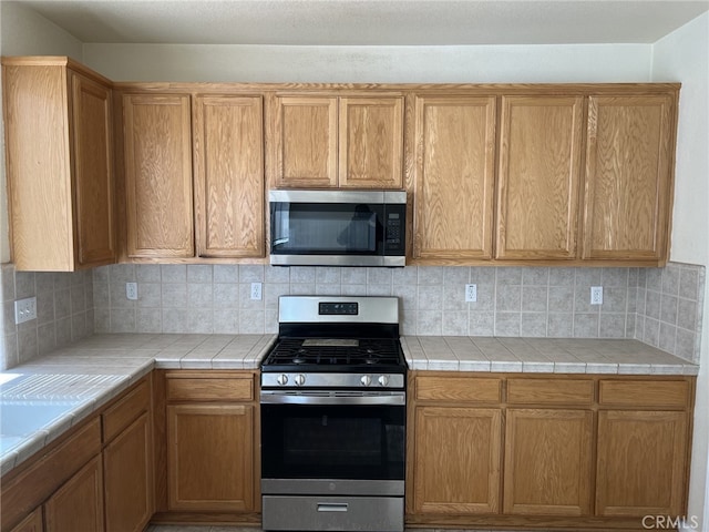 kitchen featuring tile countertops, tasteful backsplash, and stainless steel appliances