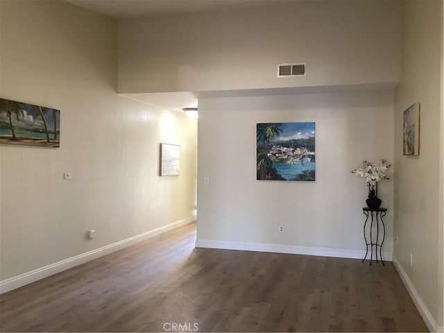 empty room with visible vents, baseboards, and wood finished floors