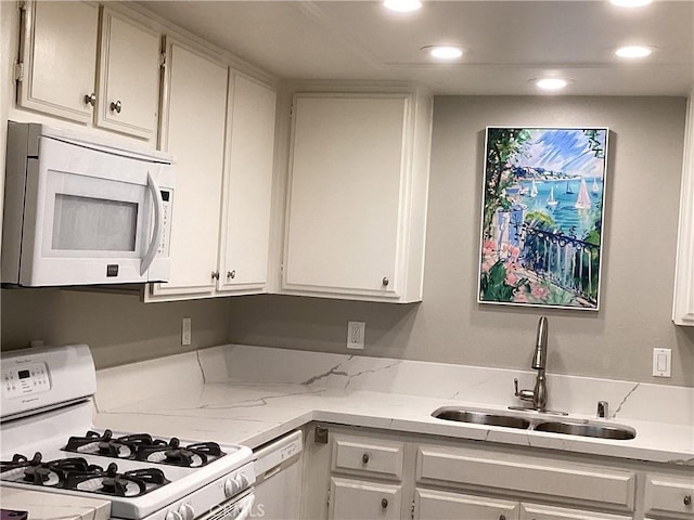 kitchen featuring recessed lighting, white appliances, a sink, white cabinets, and light stone countertops