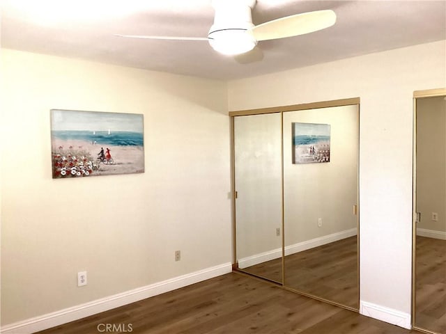 unfurnished bedroom featuring ceiling fan, two closets, baseboards, and wood finished floors