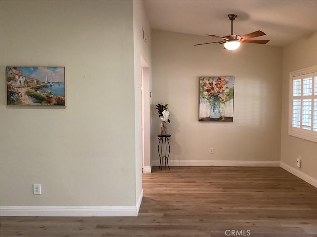 spare room with ceiling fan, baseboards, and wood finished floors