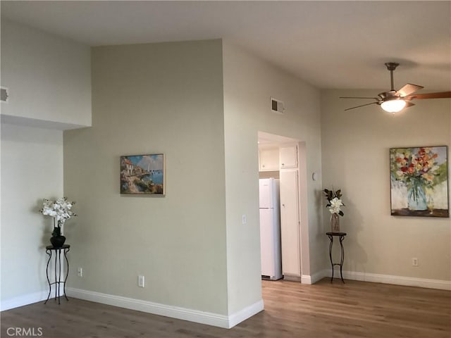 empty room with baseboards, visible vents, ceiling fan, and wood finished floors