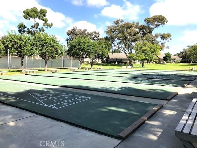 view of property's community with a yard, fence, and shuffleboard