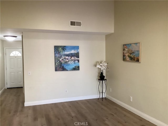 unfurnished room featuring baseboards, visible vents, and wood finished floors