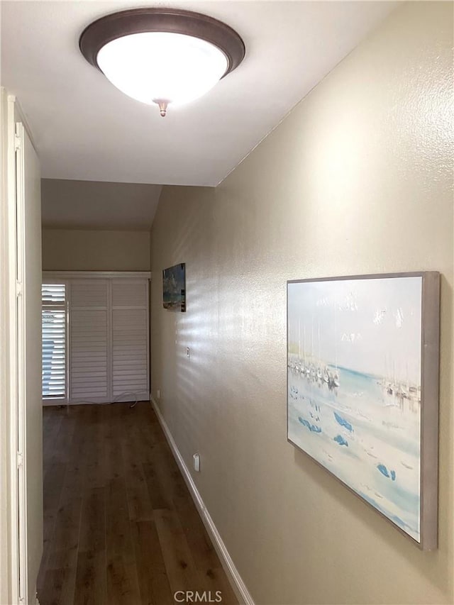 hall featuring vaulted ceiling, wood finished floors, and baseboards