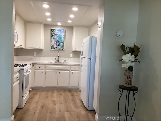 kitchen with white appliances, a sink, white cabinets, light countertops, and light wood-type flooring