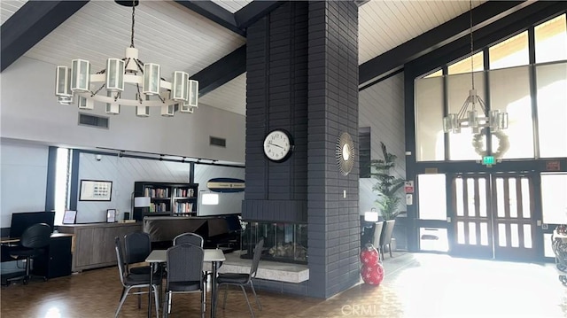 dining room featuring an inviting chandelier, visible vents, a brick fireplace, and high vaulted ceiling