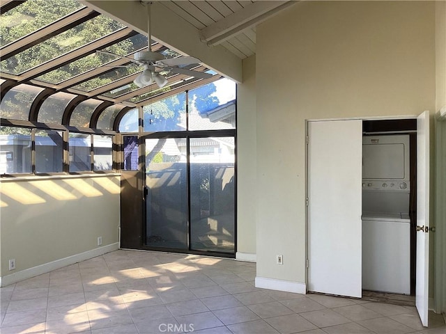 unfurnished sunroom with stacked washer / drying machine and beam ceiling