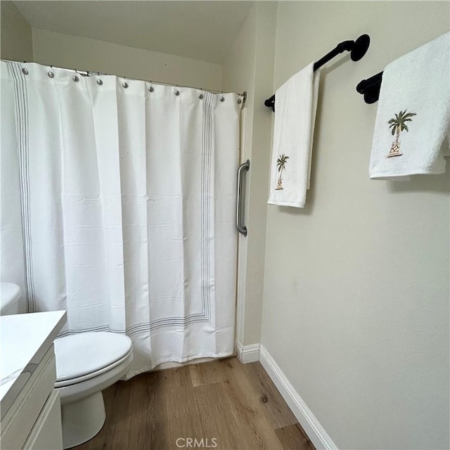 full bathroom with a shower with shower curtain, toilet, vanity, wood finished floors, and baseboards