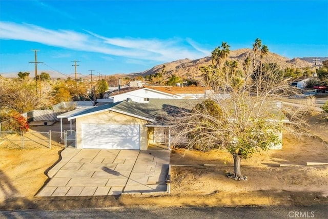 view of front of property featuring concrete driveway, fence, an attached garage, and a mountain view