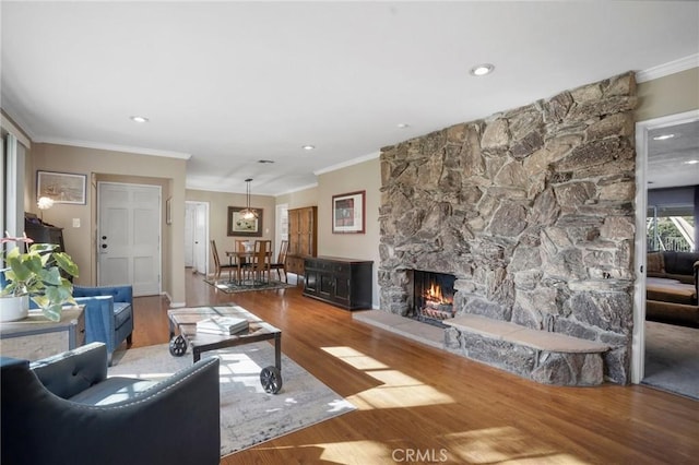 living area with recessed lighting, ornamental molding, a fireplace, and wood finished floors