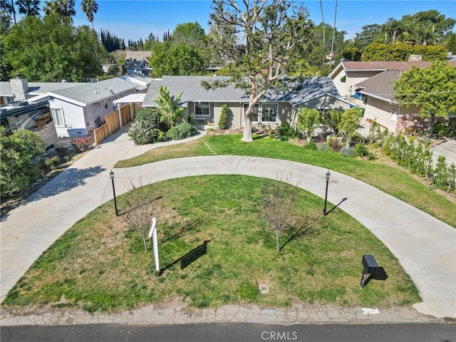 view of front facade with a residential view, curved driveway, and a front yard