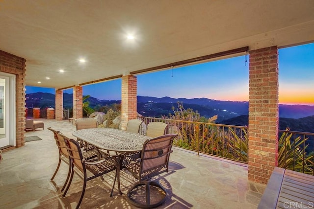 patio terrace at dusk with outdoor dining space and a mountain view