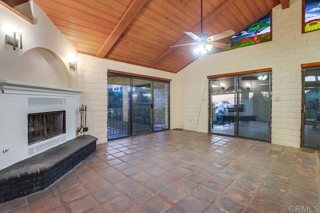 unfurnished living room with exterior fireplace, beamed ceiling, wood ceiling, and a ceiling fan