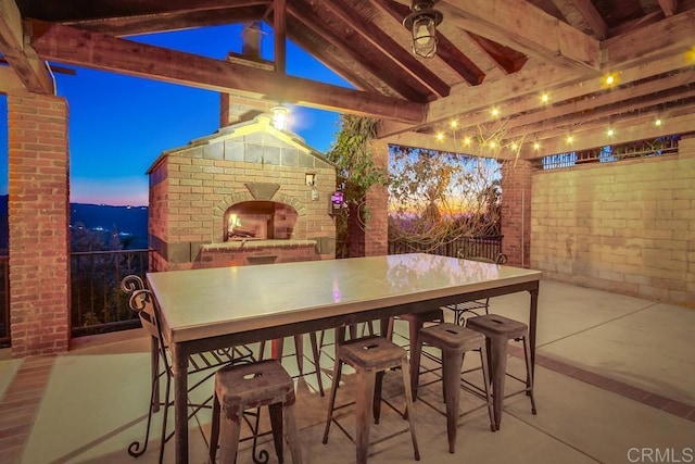 patio terrace at dusk with an outdoor brick fireplace and outdoor dry bar