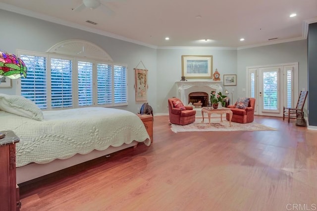 bedroom featuring a fireplace, ornamental molding, and wood finished floors