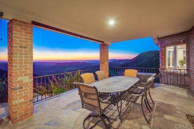 patio terrace at dusk with outdoor dining area and a mountain view