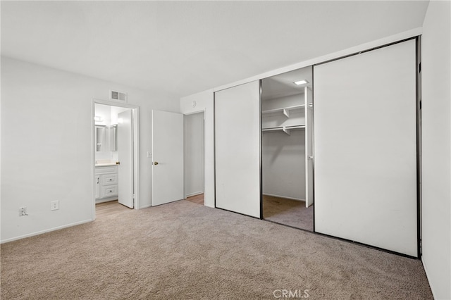 unfurnished bedroom with ensuite bath, carpet, and a closet