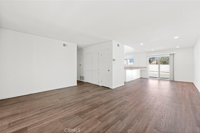 unfurnished living room featuring baseboards, visible vents, dark wood finished floors, and recessed lighting