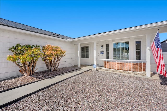 property entrance with a garage, covered porch, and roof with shingles