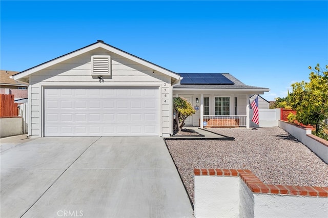 ranch-style home featuring a garage, solar panels, concrete driveway, and fence