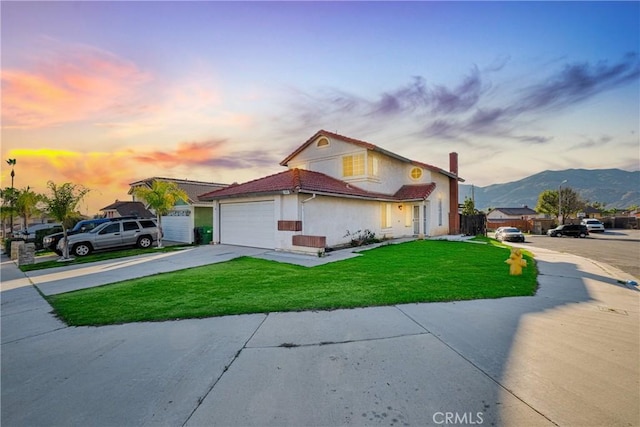 view of front of house featuring an attached garage, a mountain view, driveway, stucco siding, and a front yard