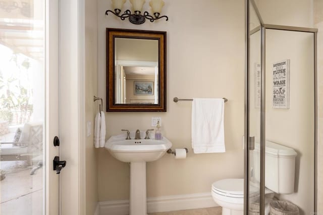 bathroom with a shower stall, toilet, and baseboards