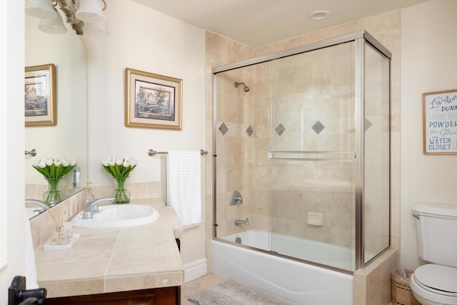 full bath featuring tile patterned flooring, vanity, toilet, and bath / shower combo with glass door