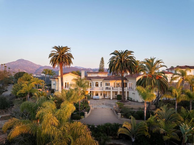 rear view of property with a chimney, stucco siding, stairway, a mountain view, and a balcony