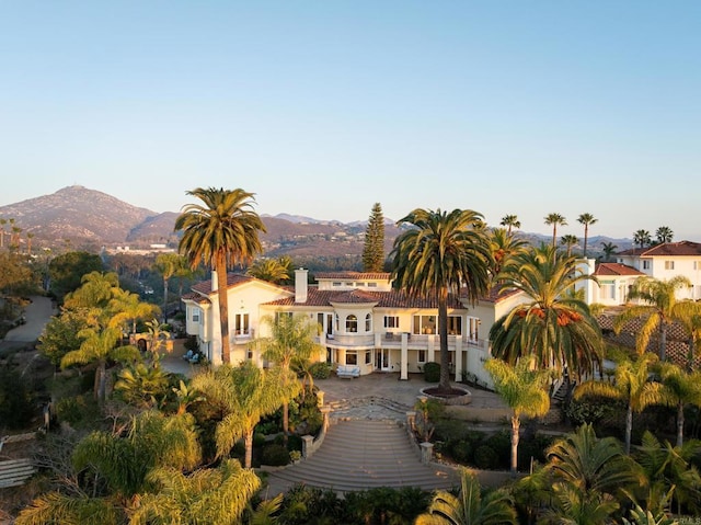 rear view of property with a mountain view, a balcony, and stucco siding