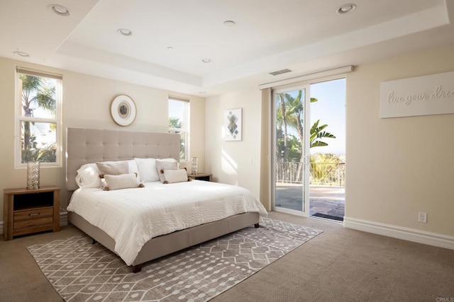 bedroom with access to exterior, a tray ceiling, carpet, and baseboards