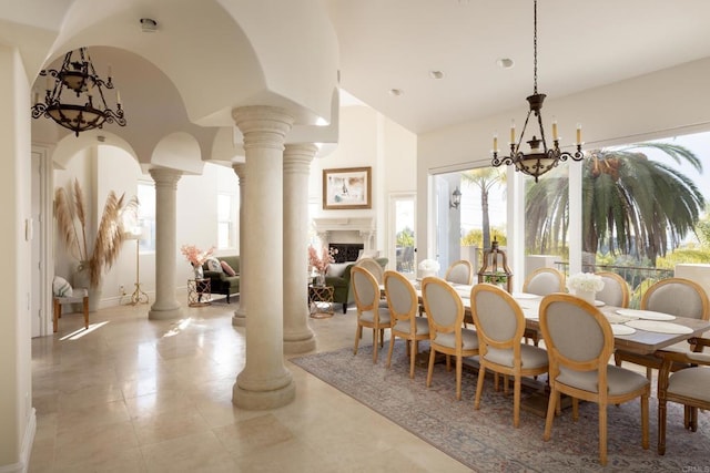 dining space with arched walkways, a fireplace, lofted ceiling, a chandelier, and ornate columns