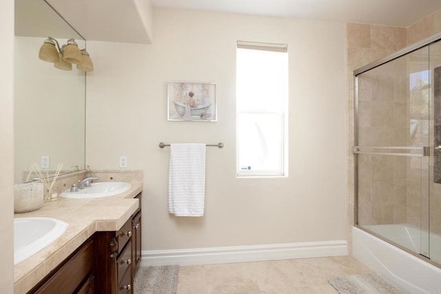 full bath with shower / bath combination with glass door, a sink, baseboards, and double vanity