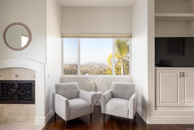 sitting room with a fireplace, baseboards, and dark wood finished floors