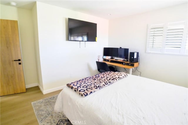 bedroom featuring baseboards and light wood finished floors