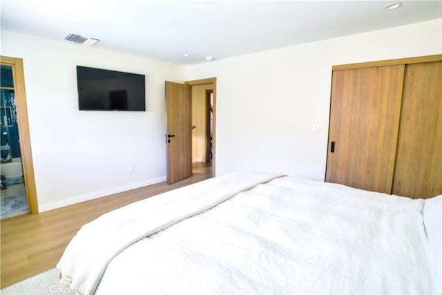 bedroom featuring recessed lighting, wood finished floors, visible vents, baseboards, and a closet