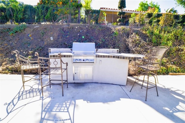 view of patio with exterior kitchen, grilling area, and fence