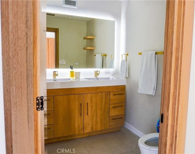 bathroom featuring visible vents, toilet, vanity, baseboards, and tile patterned floors