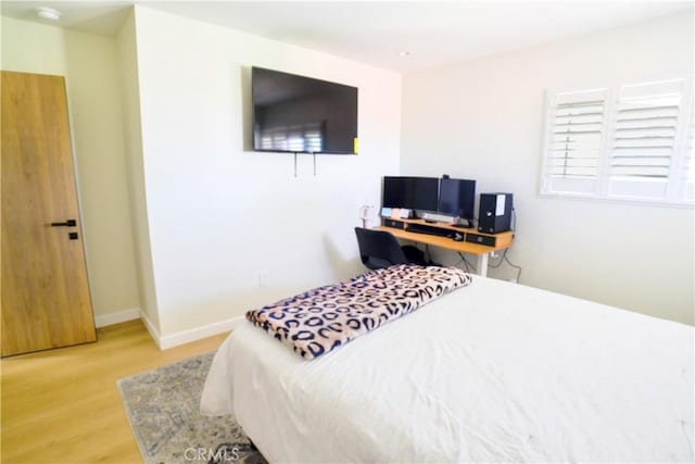 bedroom featuring light wood finished floors and baseboards