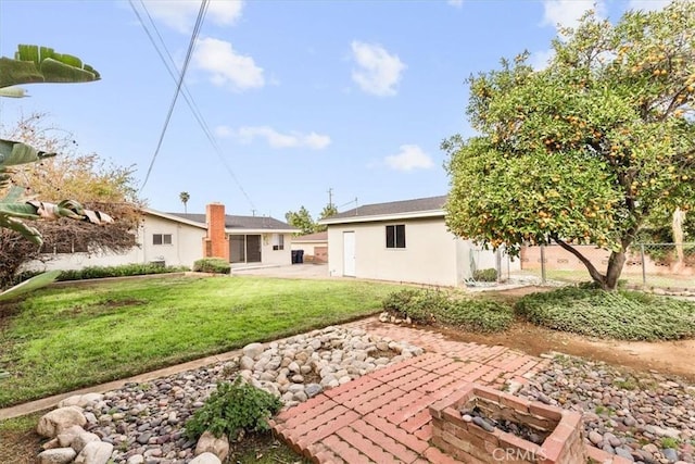 back of house featuring an outdoor fire pit, fence, a lawn, stucco siding, and a patio area