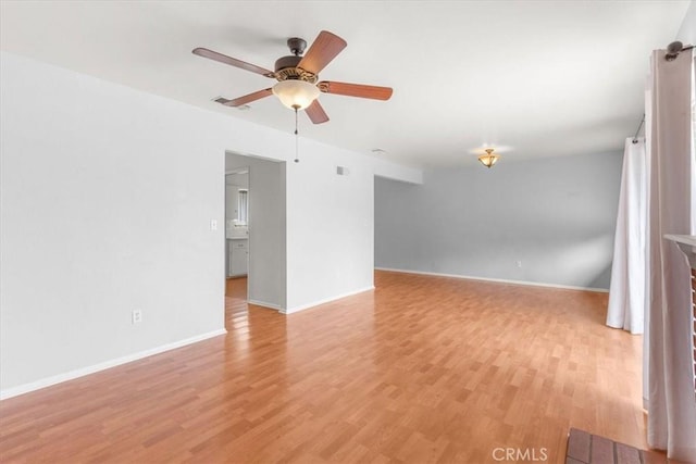 spare room with light wood-style floors, ceiling fan, visible vents, and baseboards