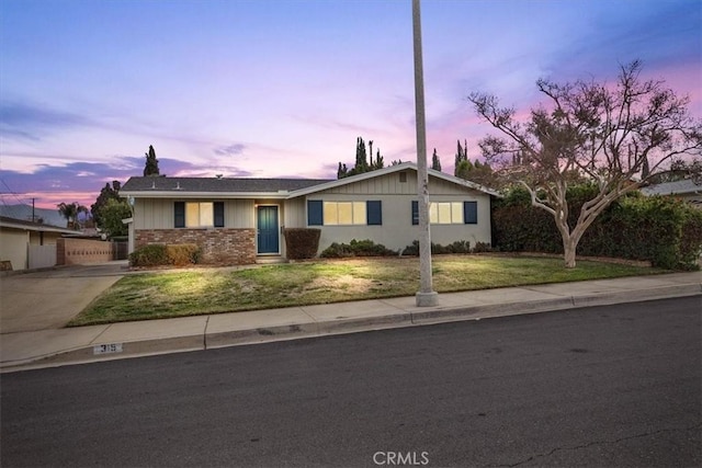 ranch-style home featuring concrete driveway and a front yard