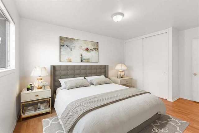 bedroom with multiple windows, a closet, and wood finished floors