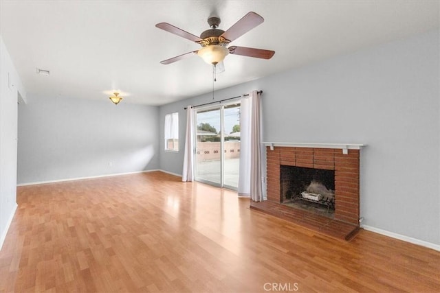 unfurnished living room with light wood-type flooring, a fireplace, baseboards, and ceiling fan