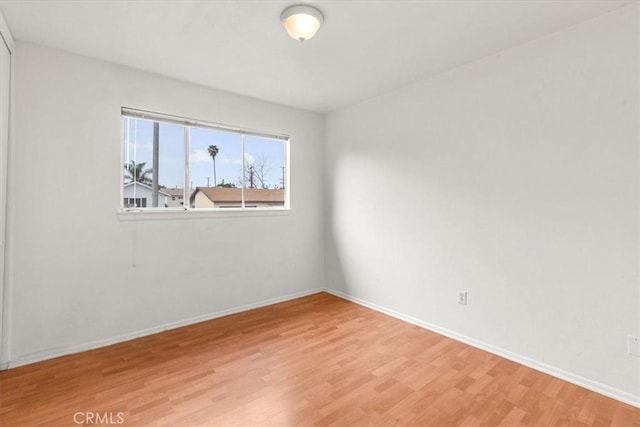 spare room featuring light wood-style flooring and baseboards